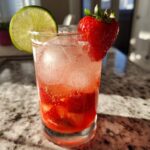 A vibrant Strawberry Lime Vodka Smash cocktail with fresh strawberries, lime, and ice.