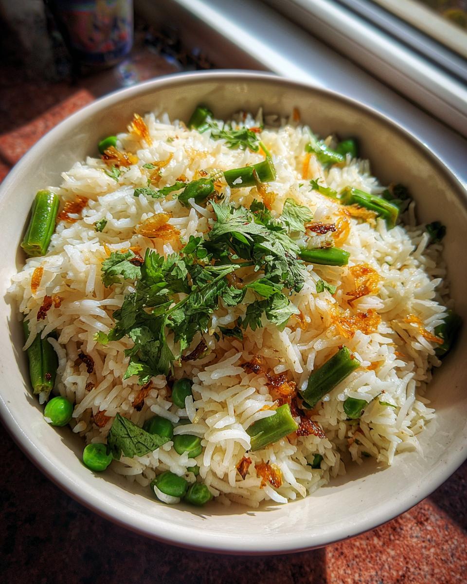 Overhead shot of Sweet Pea & Shallot Pulao in a white bowl, garnished with cilantro.