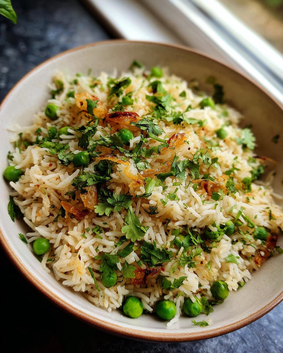 Close-up of Sweet Pea & Shallot Pulao in a bowl, garnished with fresh cilantro and fried shallots.
