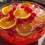 Close-up of a bowl of Vodka Party Punch with orange slices, cherries, and ice.