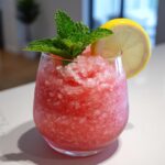 A vibrant Vodka Strawberry Lemonade Slushy garnished with mint and a lemon slice, perfect for summer parties.